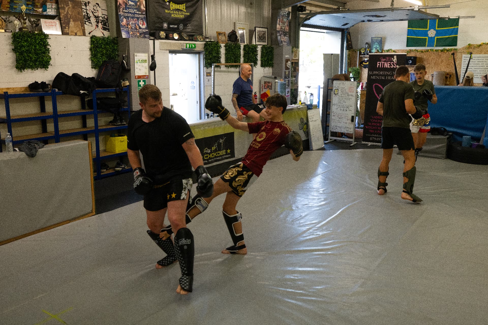 Junior member landing a body kick on the coach's pads