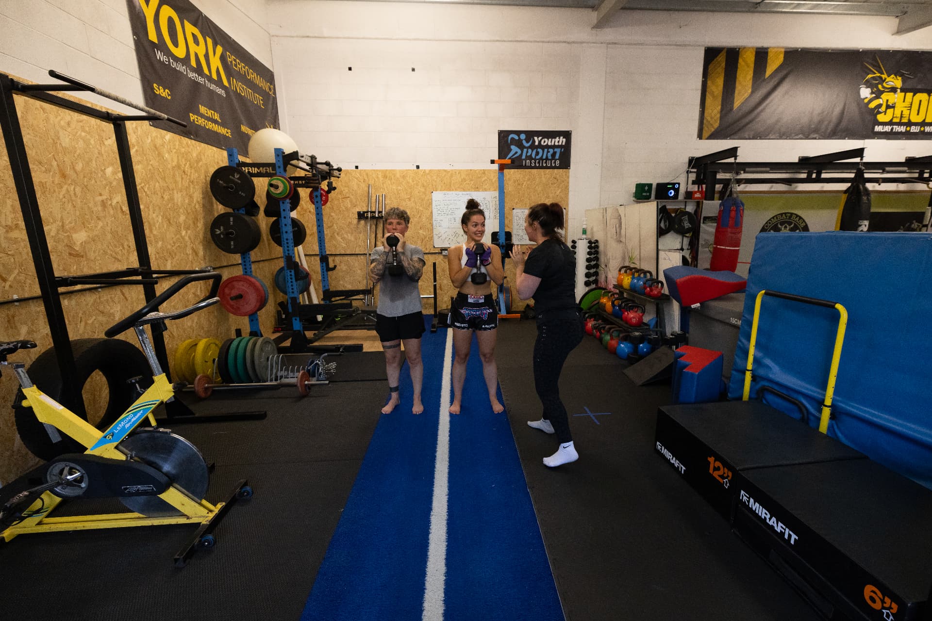 Coach leading a dumbbell front squat drill in the strength area