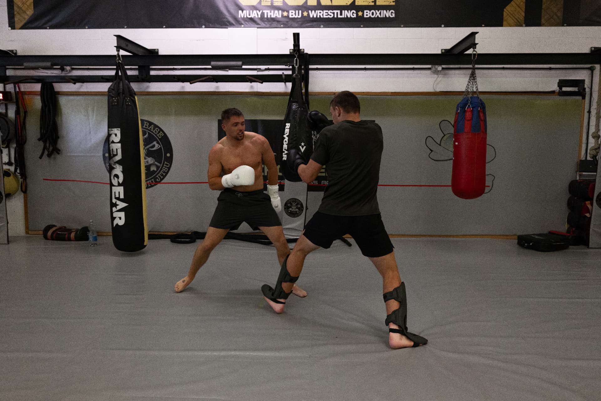 Two members circling in a sparring round beside the heavy bags