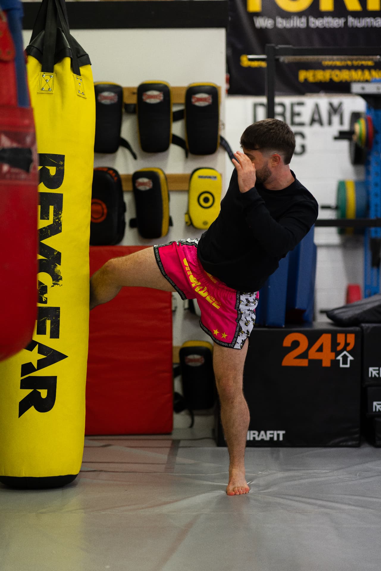 Coach landing a Muay Thai roundhouse on the heavy bag