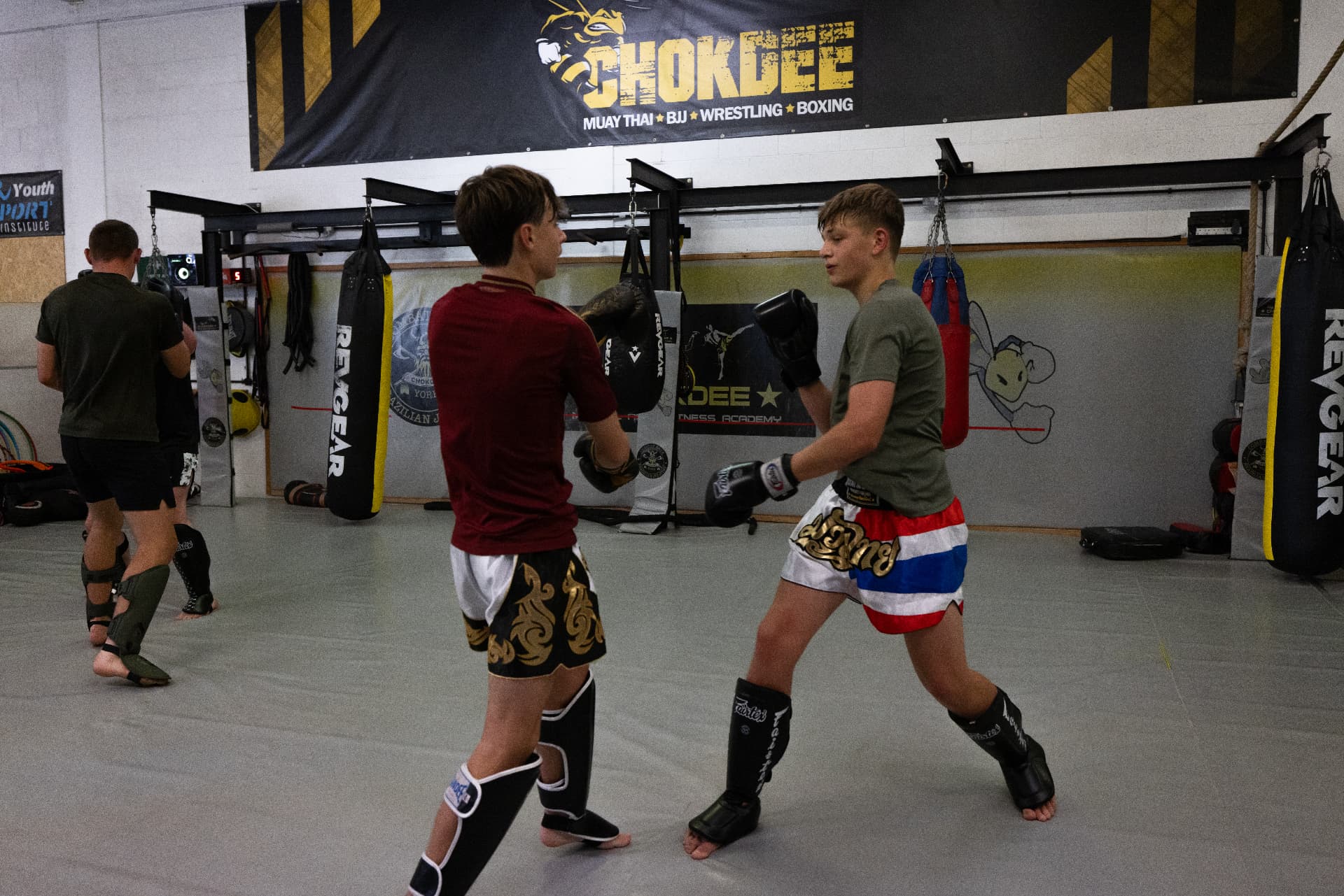 Two teenage Muay Thai members sparring beneath the Chokdee banner