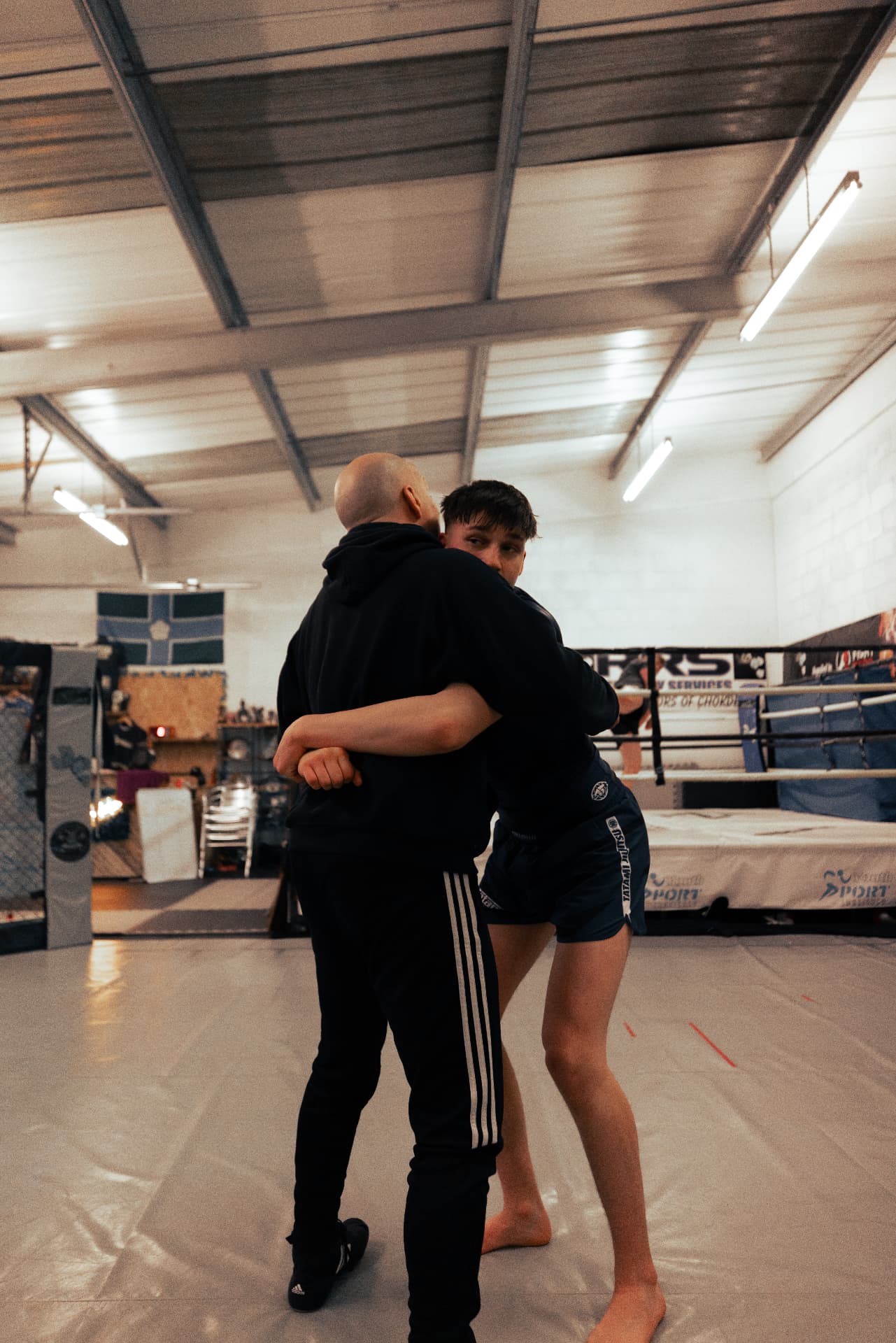 Two members drilling the Muay Thai clinch on the mats