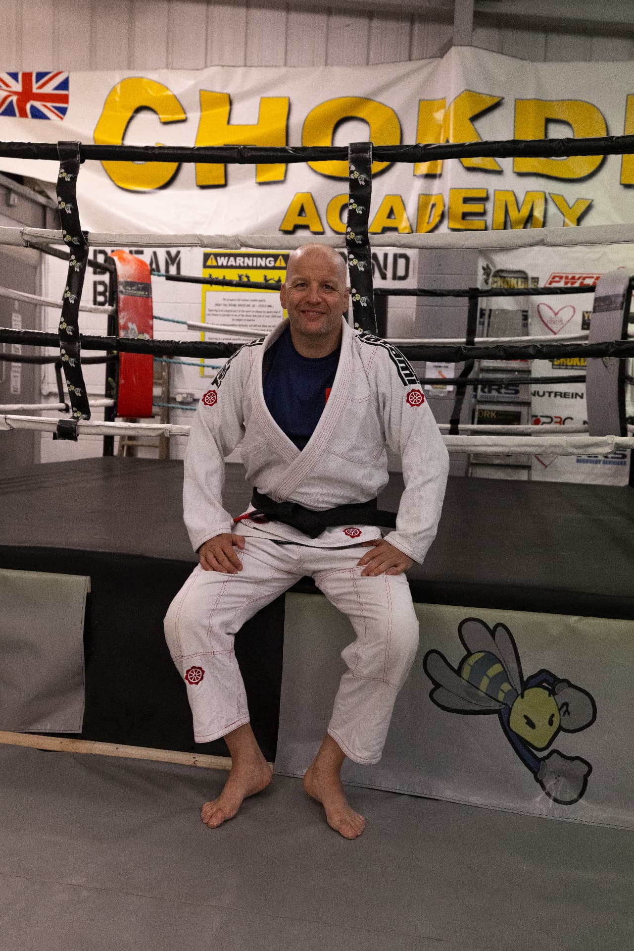Coach Rich Cadden in his black belt gi sat ringside at Chokdee Academy