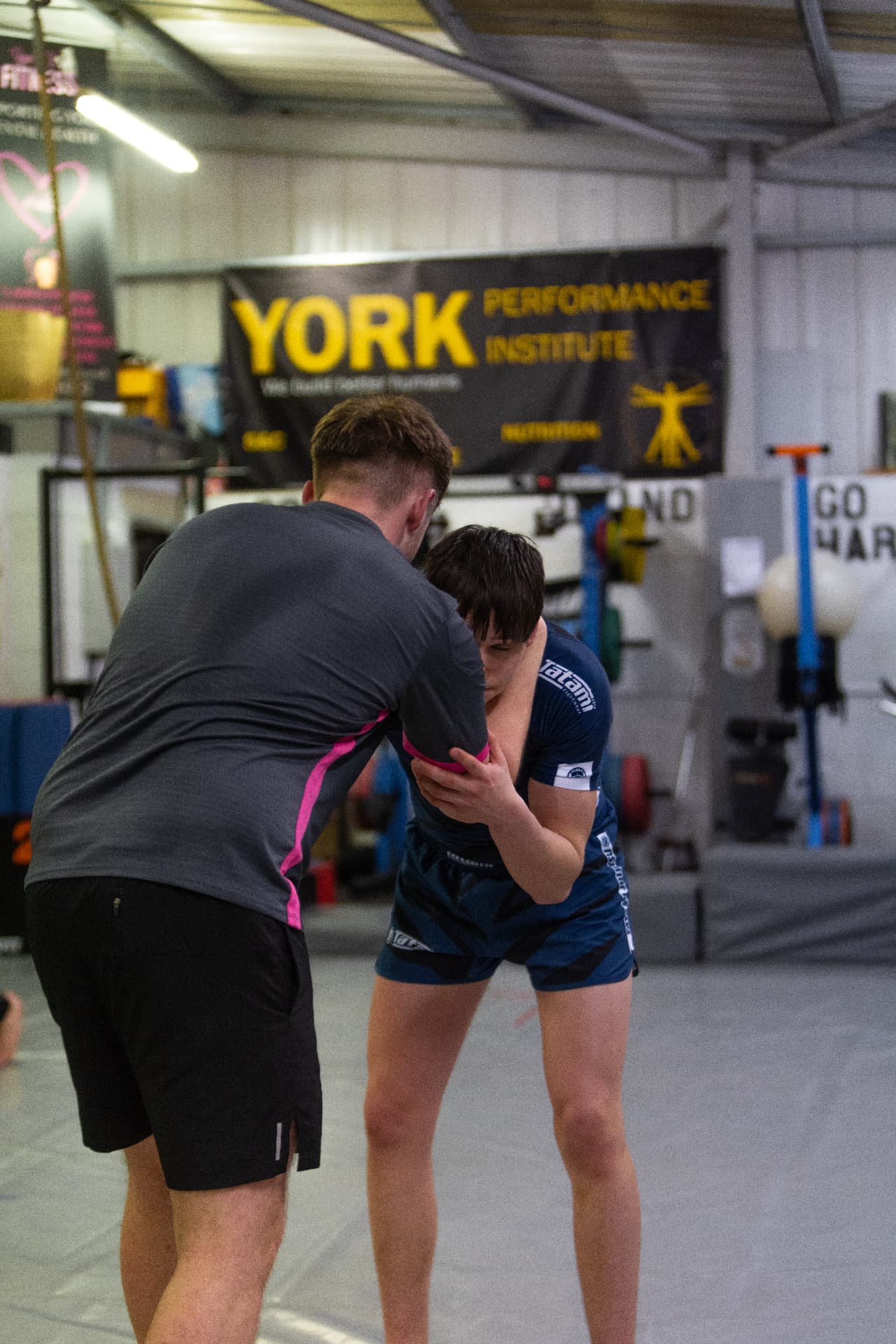 Two athletes drilling a clinch takedown on the mats