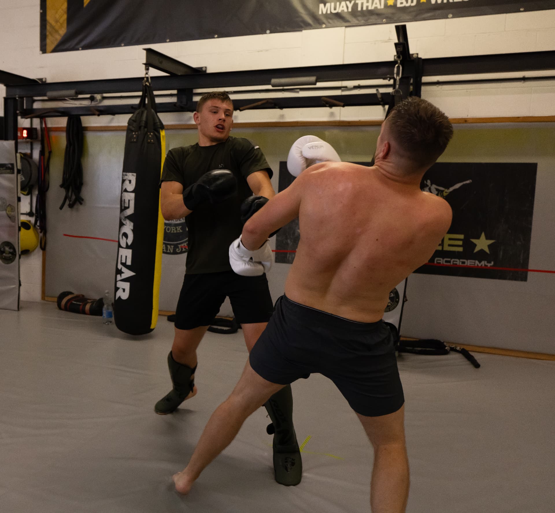 Member landing a cross during technical sparring by the heavy bags