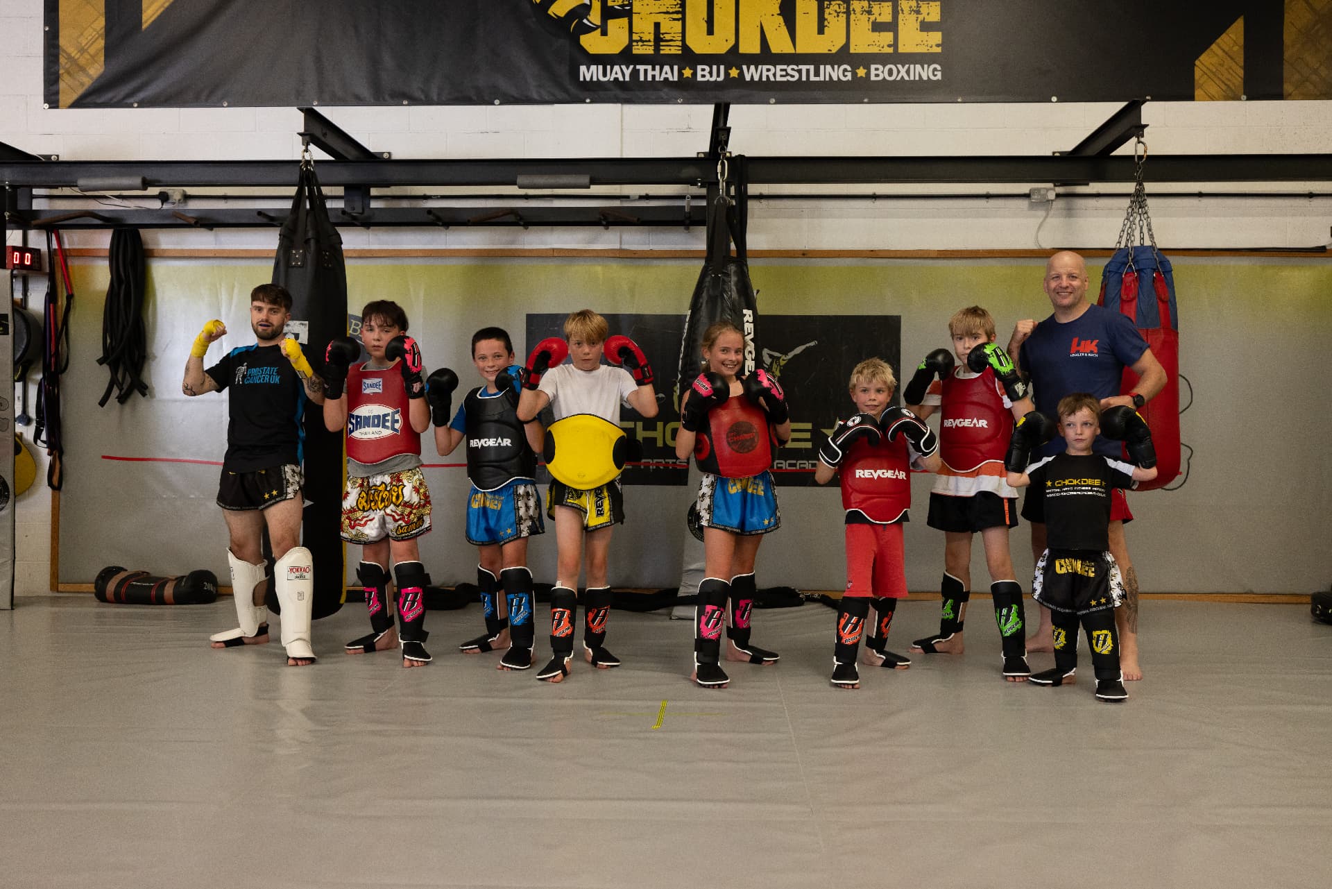 Kids Muay Thai class lined up in gloves and shin pads under the Chokdee banner